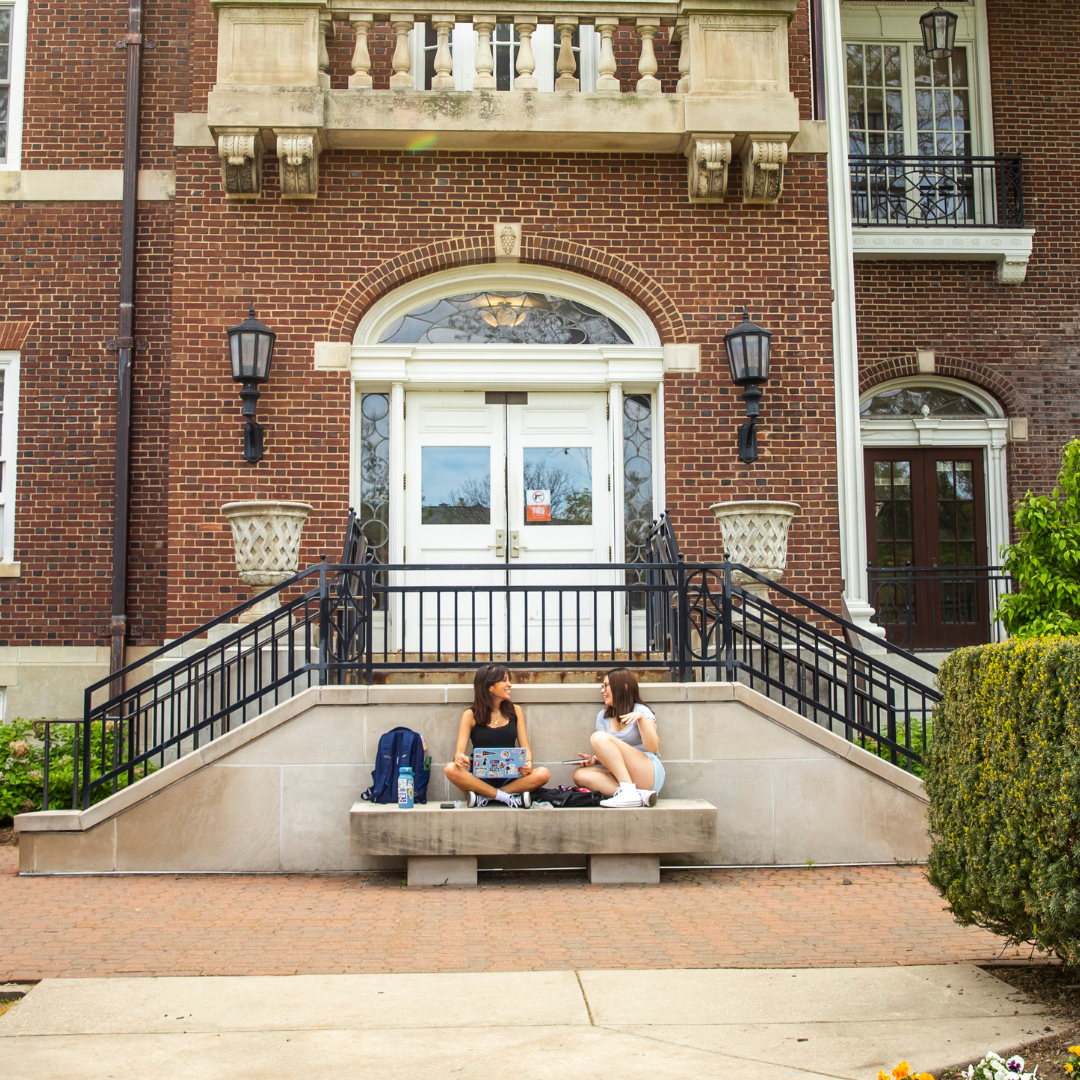 Two students studying outside of the English building.
