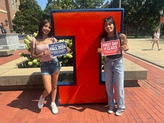 Ariana and her older sister in front of a Block-I with signs reading "Fall 2024" and "First Day of Class". 