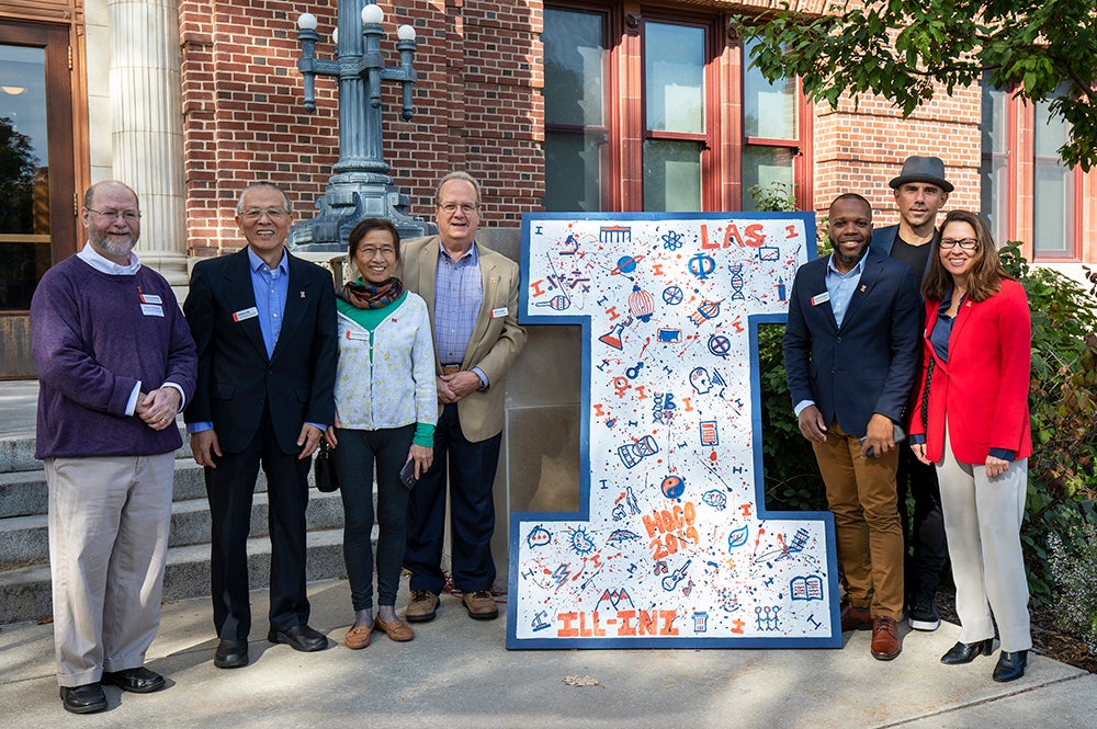 Alumni award winners pose near a wooden I decorated for Homecoming