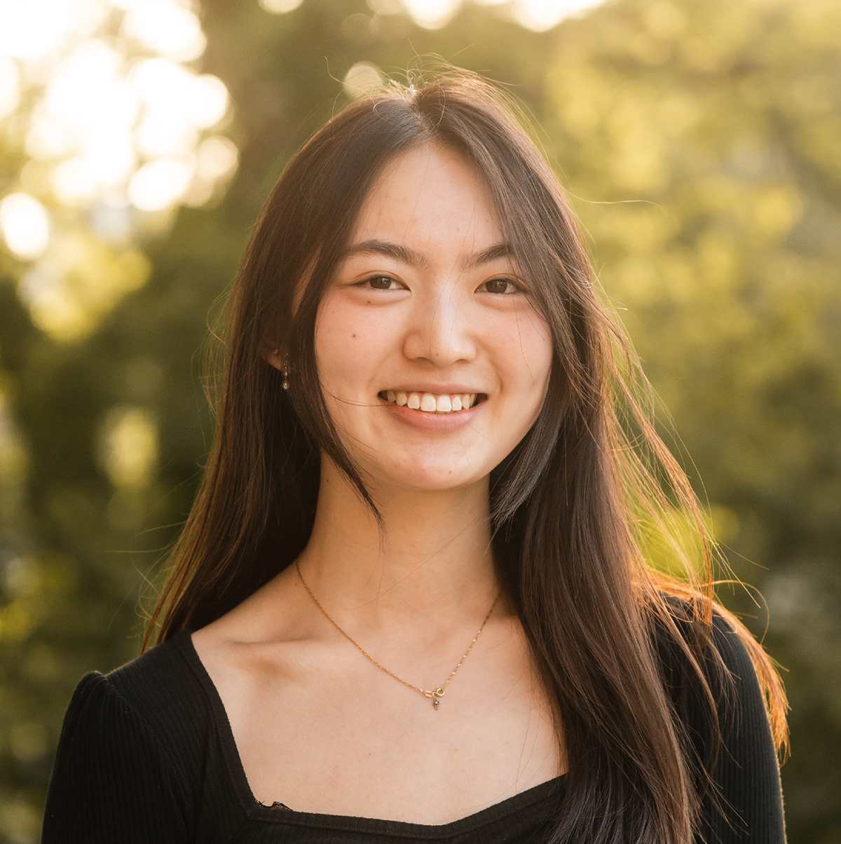 Headshot of GGIS alum Tiffany Chen with a background of green leaves being hit by sunlight