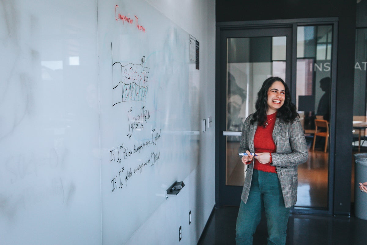 Woman doing a math equation on a whiteboard