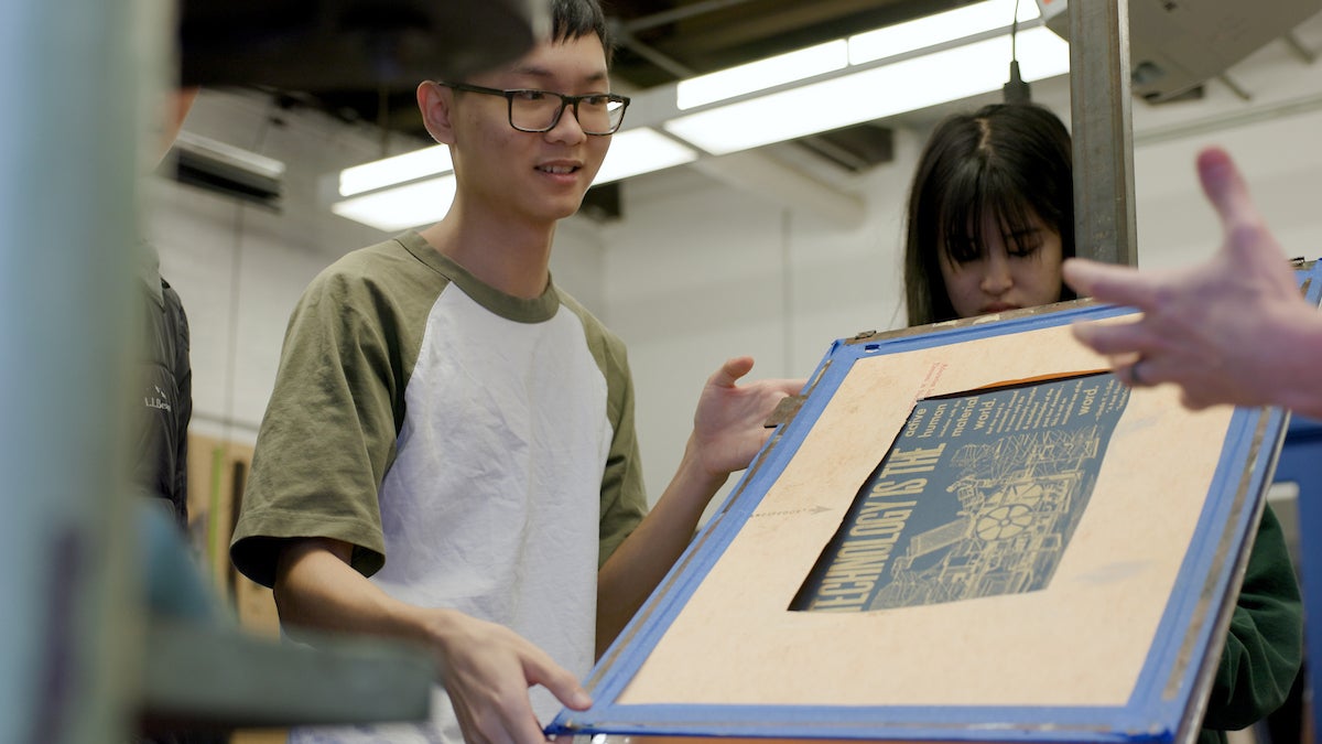 Student holding up a creation made in the Skeuomorph Press printing press