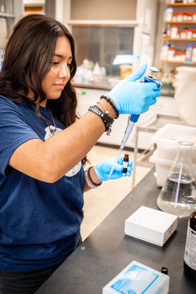 Student in lab pouring liquids into a beaker