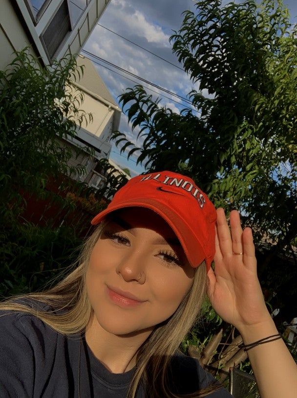 Student poses for photo on campus in orange hat