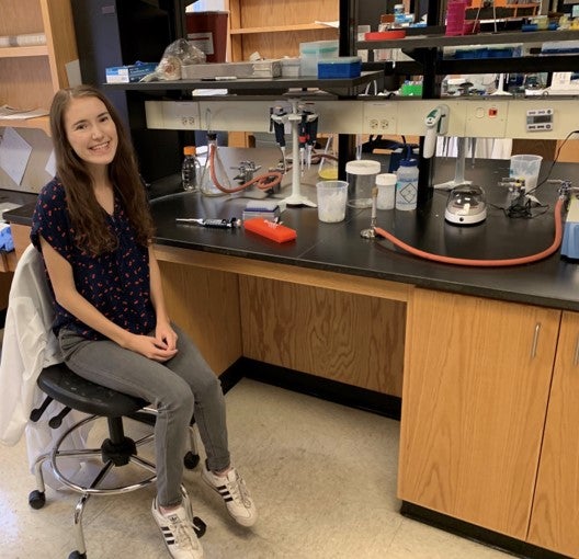 Photo of Lauren sitting at her lab on campus.
