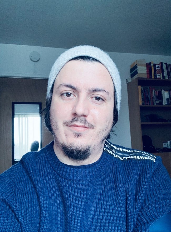 A student sits at desk with blue sweater on