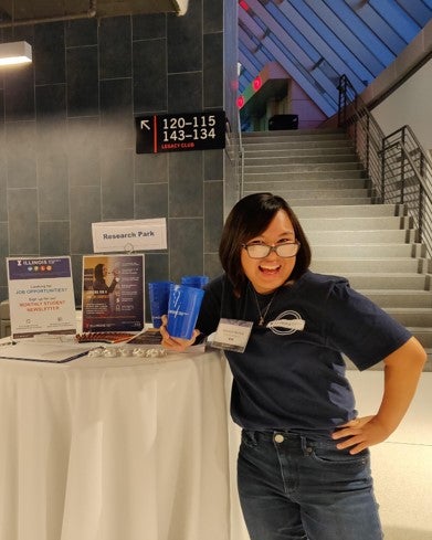 LAS junior Cherish Recera poses for a photo in front of a Research Park promotional table at the State Farm Center.