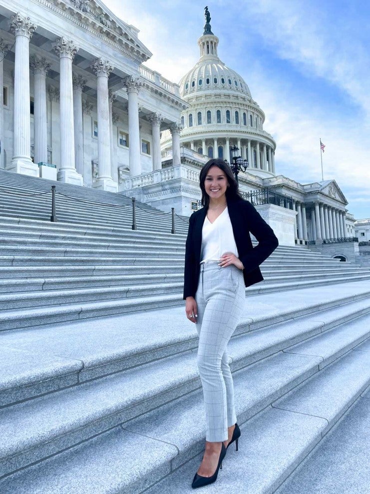 Student poses for photo in front of the US Capitol building