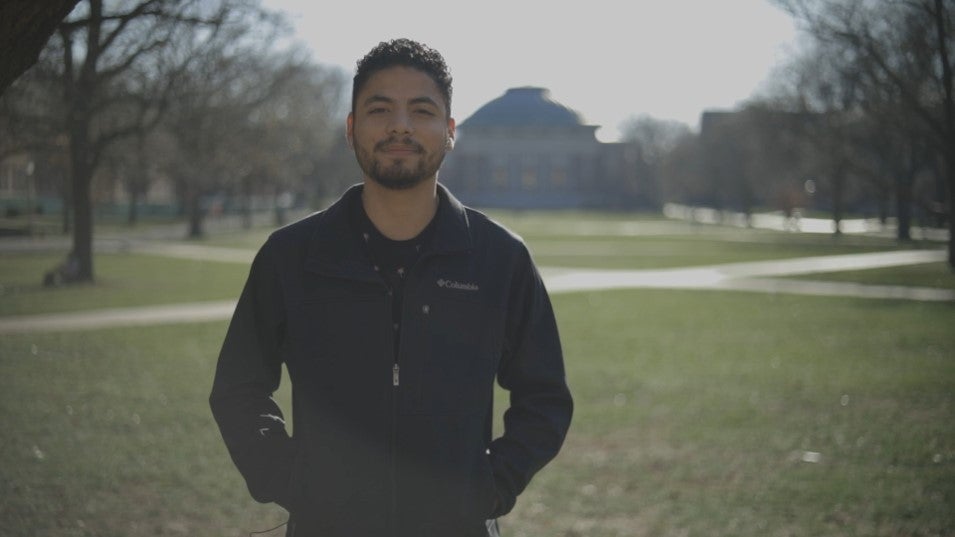 Student stands on the Quad with a black jacket on