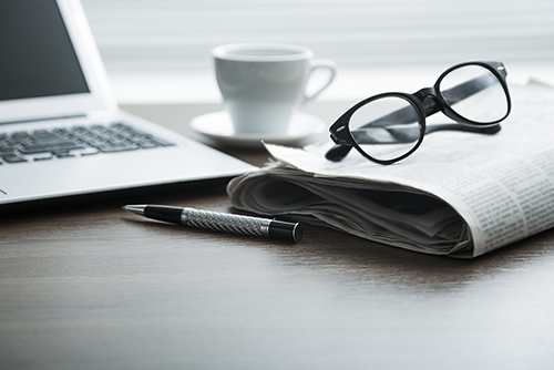 Newspaper, laptop, and glasses