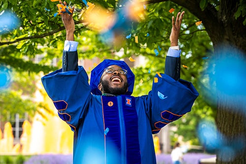 A graduate throws confetti in the air