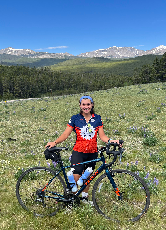 Zona with her bike on a green landscape in front of the Bighorn mountains