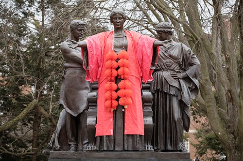 The Alma Mater statue dressed in a red robe with Chinese lanterns draped around her neck