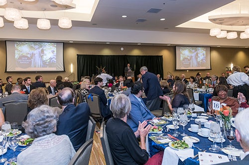 A board president addresses a full banquet audience at an alumni awards dinner