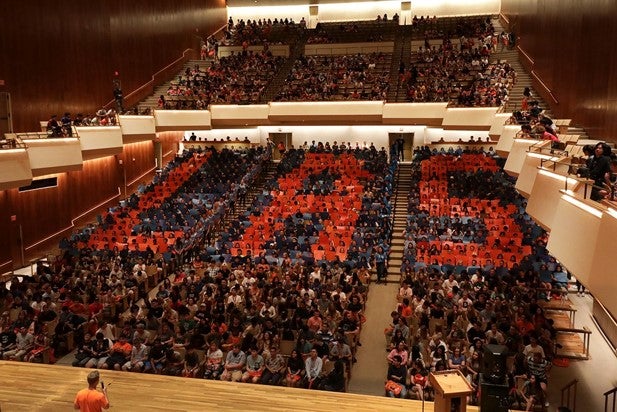 Nearly 1000 students hold up cards at freshmen orientation to spell LAS.