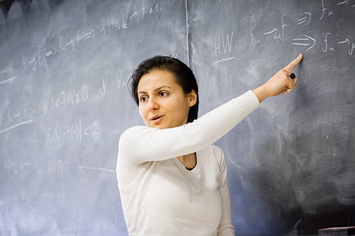 An instructor stands at a chalkboard while teaching