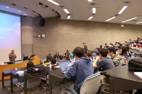 Students participate in a datathon by sitting in a large lecture-style classroom.