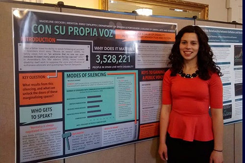Madeline Decker poses in front of a poster discussing her research