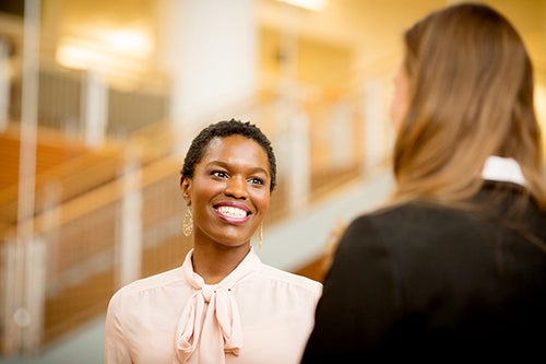 A student in professional attire networks with someone else