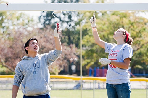 Students paint a fence as a part of a service project