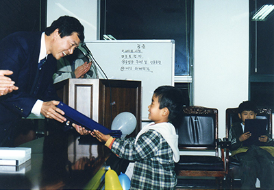Byung-Ho Chung hands a certificate to a child during a graduation ceremony at One-Two School, an organization Chung founded to help North Korean refugees adjust to life in South Korea.