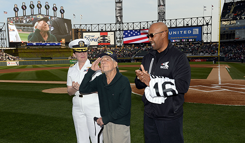 Leon Cooper, center, was honored at a Chicago White Sox game for his efforts to recover missing World War II soldiers. Former White Sox outfielder Harold Baines, right, presented Cooper with a personalized jersey. Also pictured is U.S. Navy Commander Elizabeth Zimmerman. (Photo by Ron Vesely/Chicago White Sox.)
