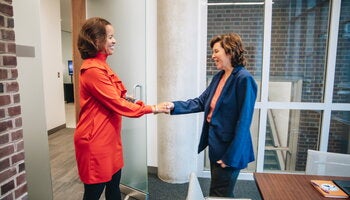 Two HR employees shaking each other's hands. 