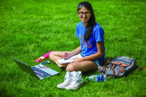 A student in an LAS T-shirt studies on the Quad.
