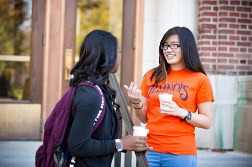 Students holding drinks talk outside Lincoln Hall.