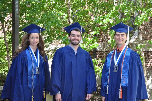 Three Lincoln Scholars in graduation regalia pose in the courtyard of Lincoln Hall