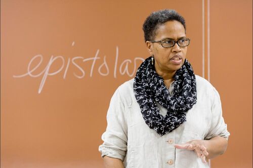 A English professor teaches poetry in front of a blackboard.