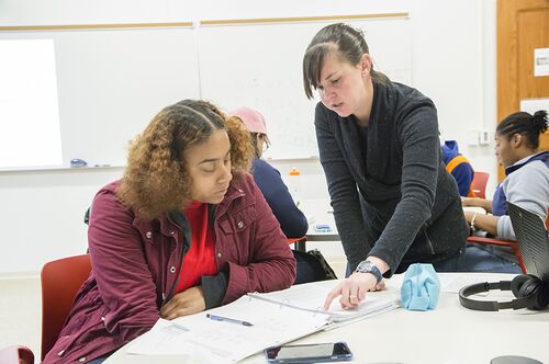 A TA helps an AAP student in class.
