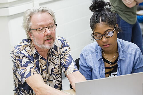 A student on her computer with a professor