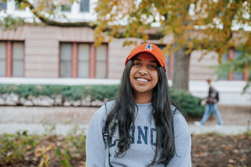 Student in Orange LAS baseball cap standing at the side entrance of Lincoln Hall between Lincoln Hall and the English Building