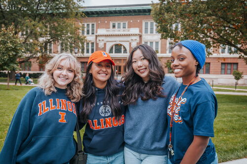 Four students taking a photo on the Main Quad across from Lincoln Hall