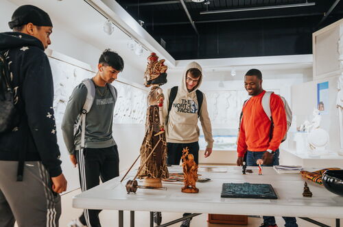 Students at the Spurlock museum gathered around a table of cultural artifacts