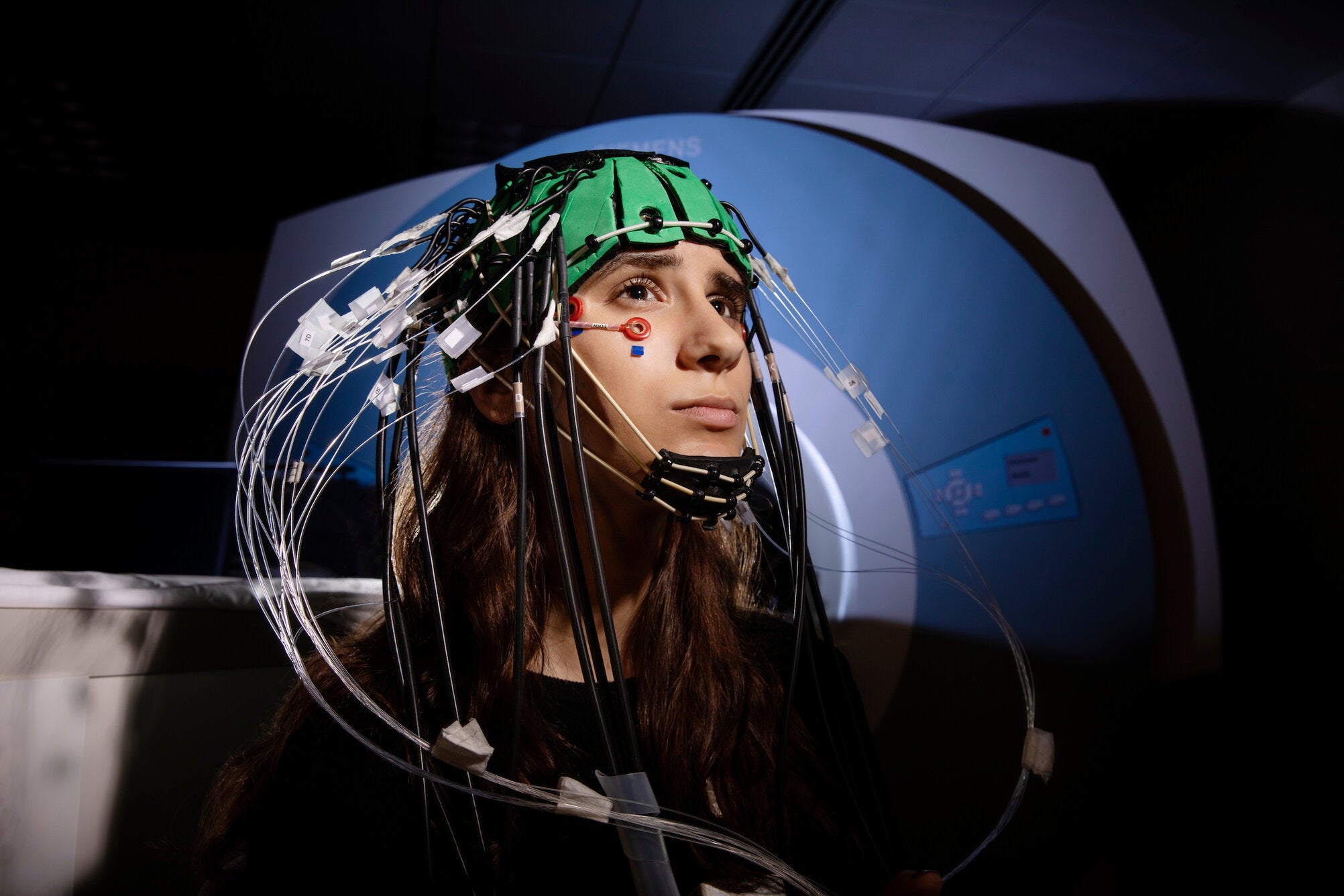 An undergraduate research assistant in the SCoPE Neuroscience Lab models a customized EROS helmet with EEG drop electrodes.