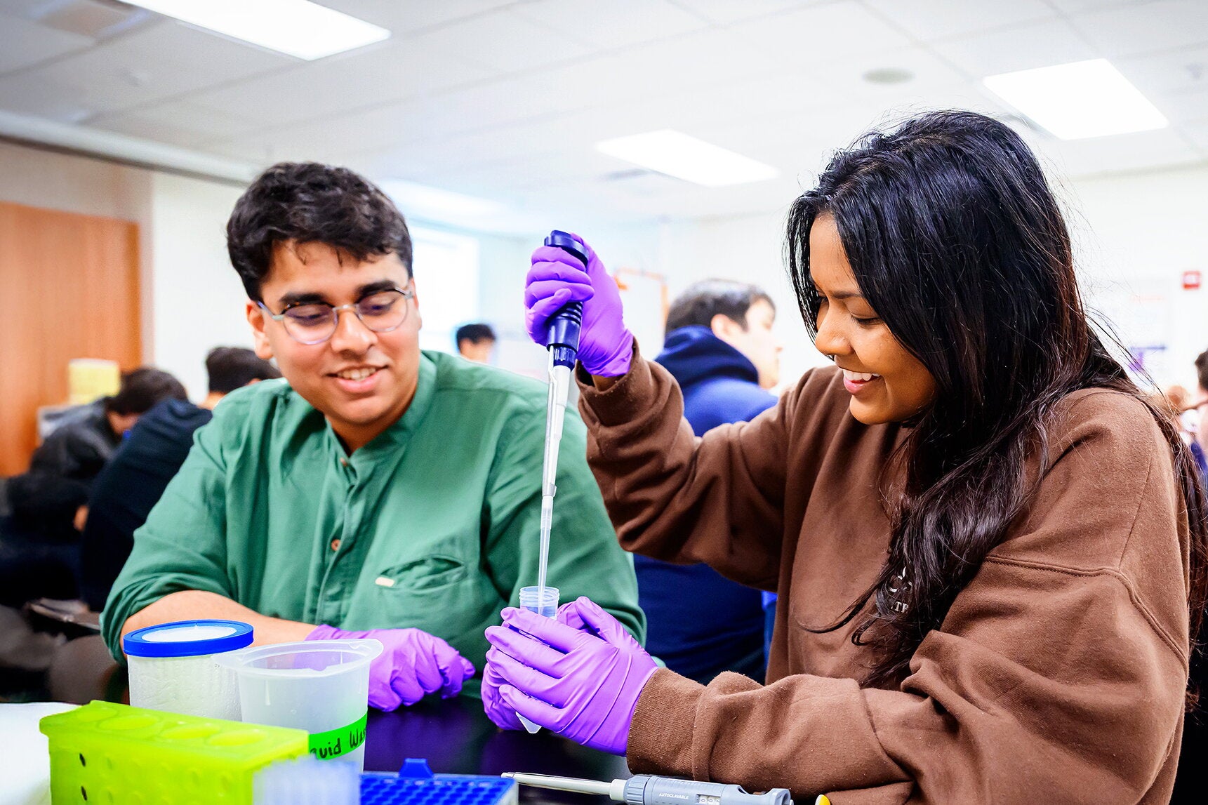 Two students in a lab with pipettes 