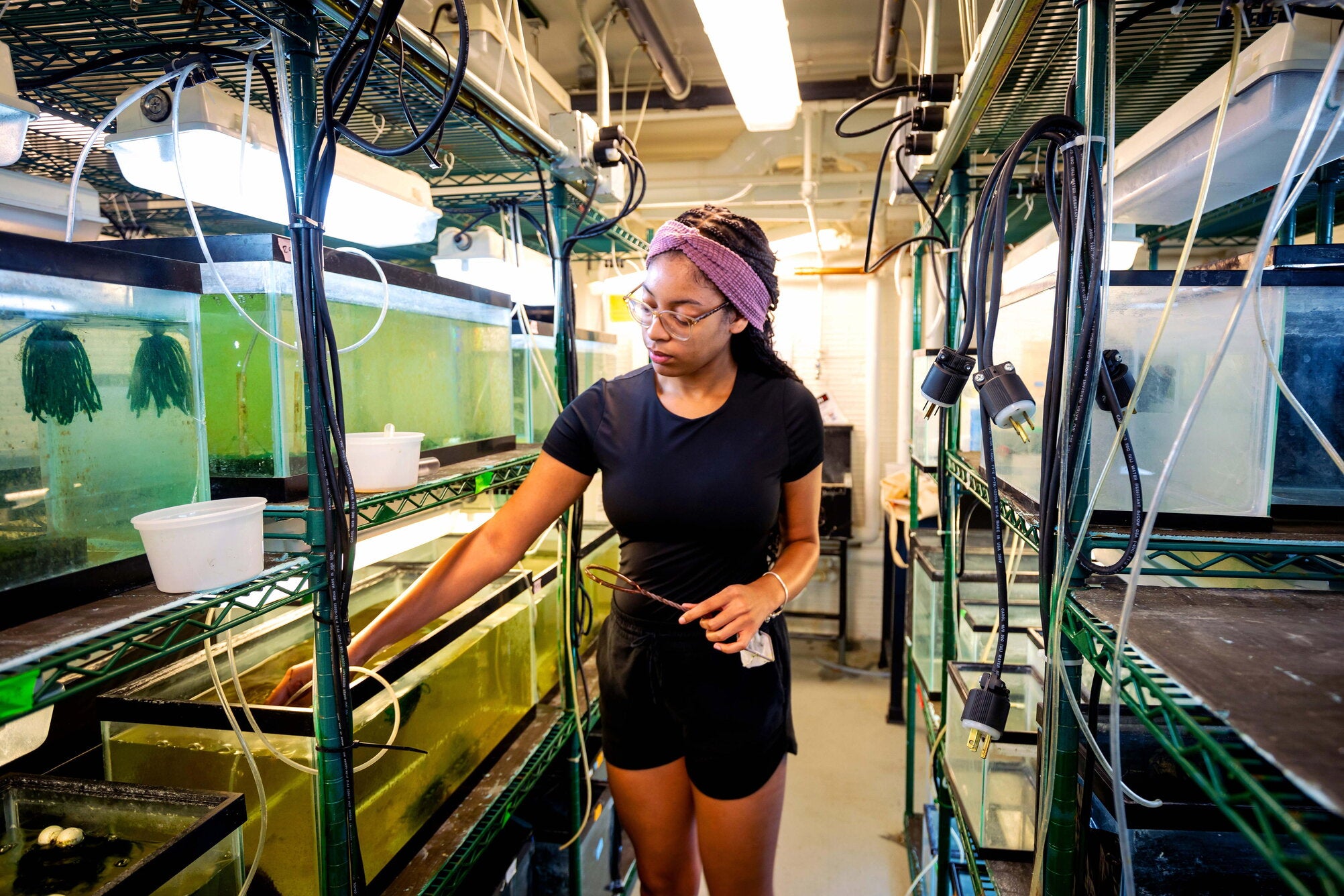 Student in a lab surrounded by fish tanks