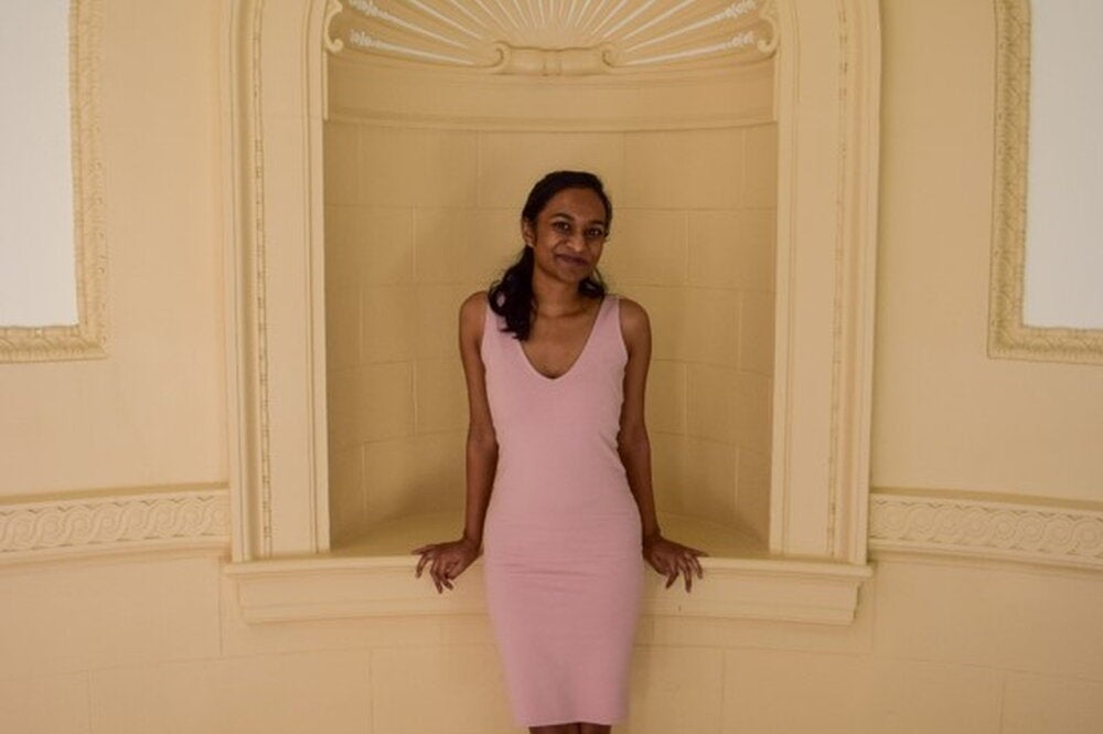LAS student poses for a photo in a pink dress against a white wall