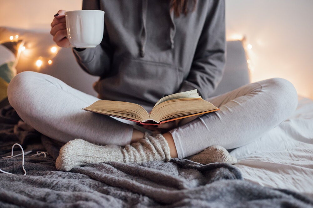 Student reading a book while drinking a cup of tea