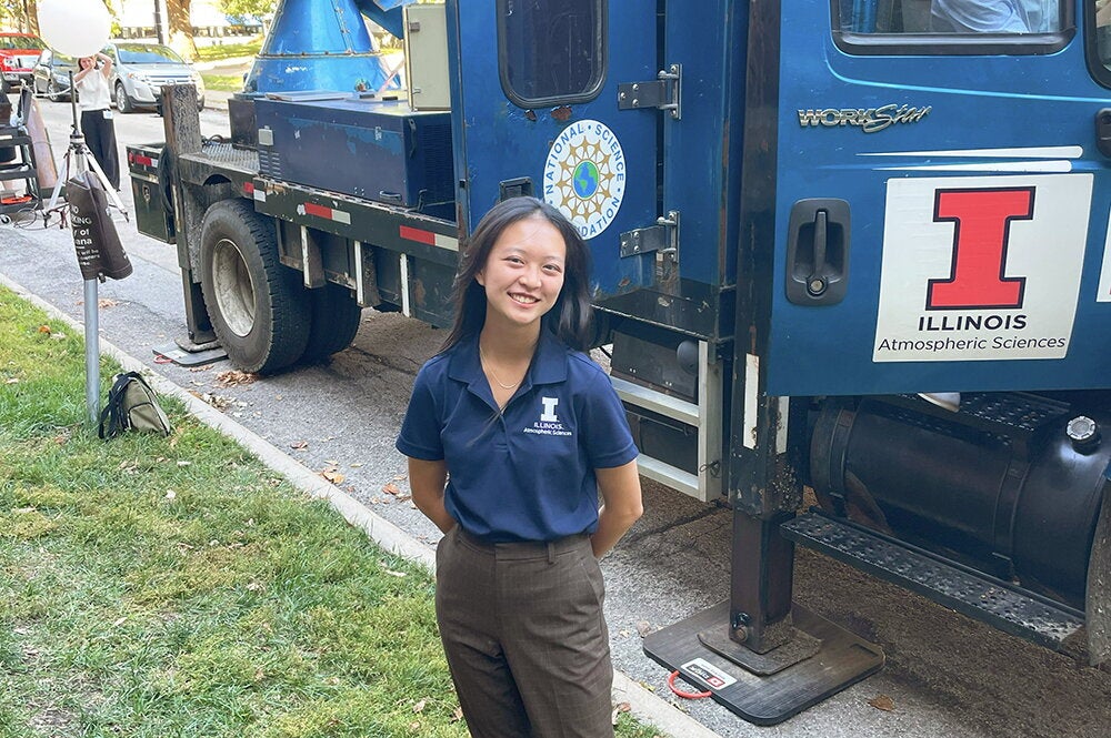 Alyssa Shih in front of a weather truck on the UIUC campus