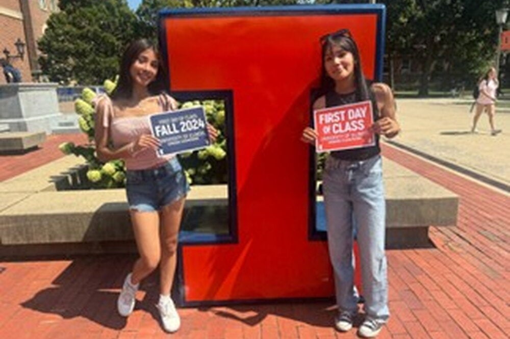 Ariana and her older sister in front of a Block-I with signs reading "Fall 2024" and "First Day of Class". 