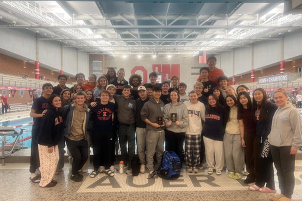 Illini Swim Club at a meet at Ohio State Univeristy. The team stands in front of the pool.