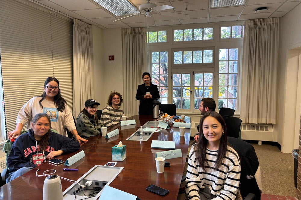 People sitting at a conference table in Coble Hall, gathering for QazTalk.
