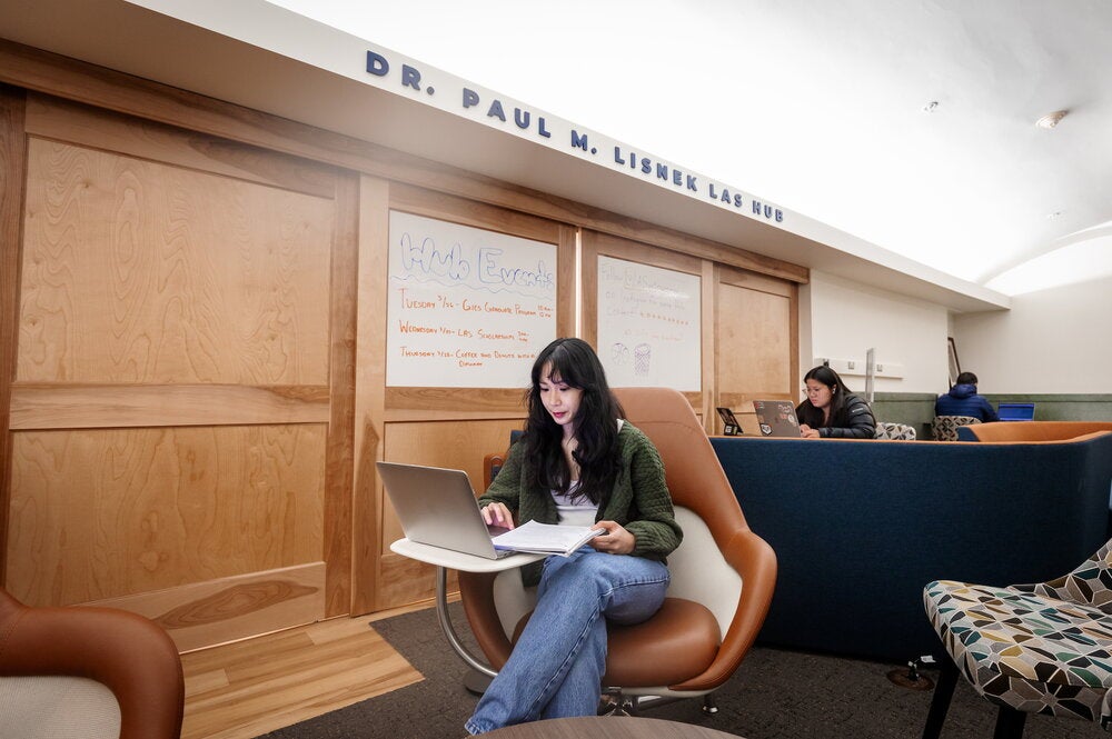 Student sitting in chair in a study space with their laptop open. 