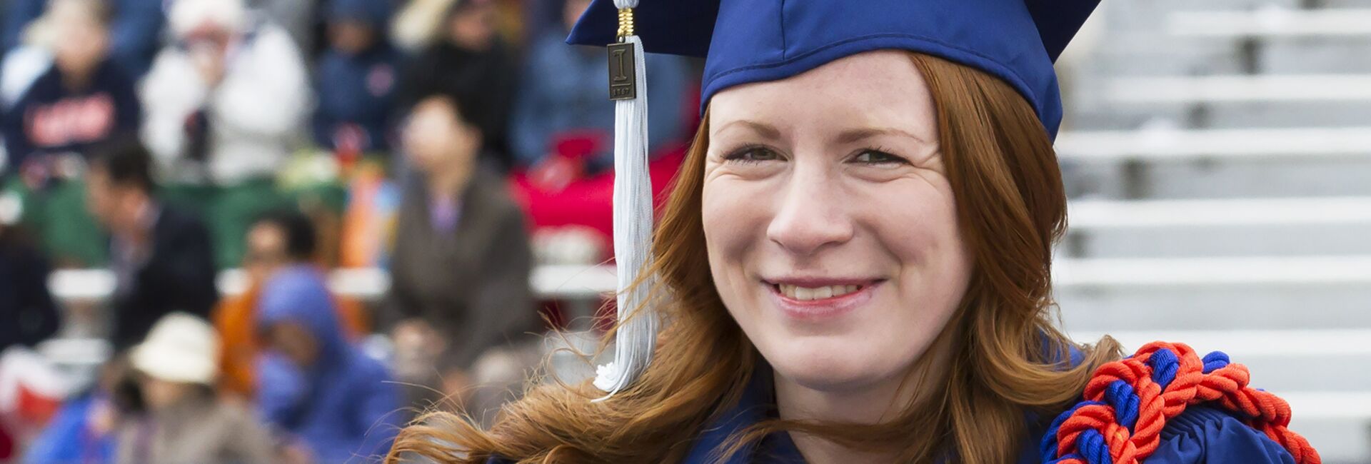 A student wearing a cap and gown smiles