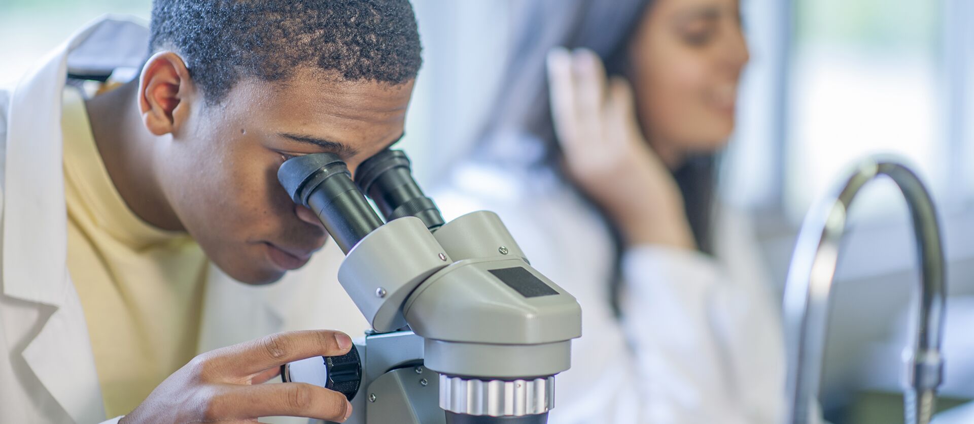 A researcher peers into a microscope
