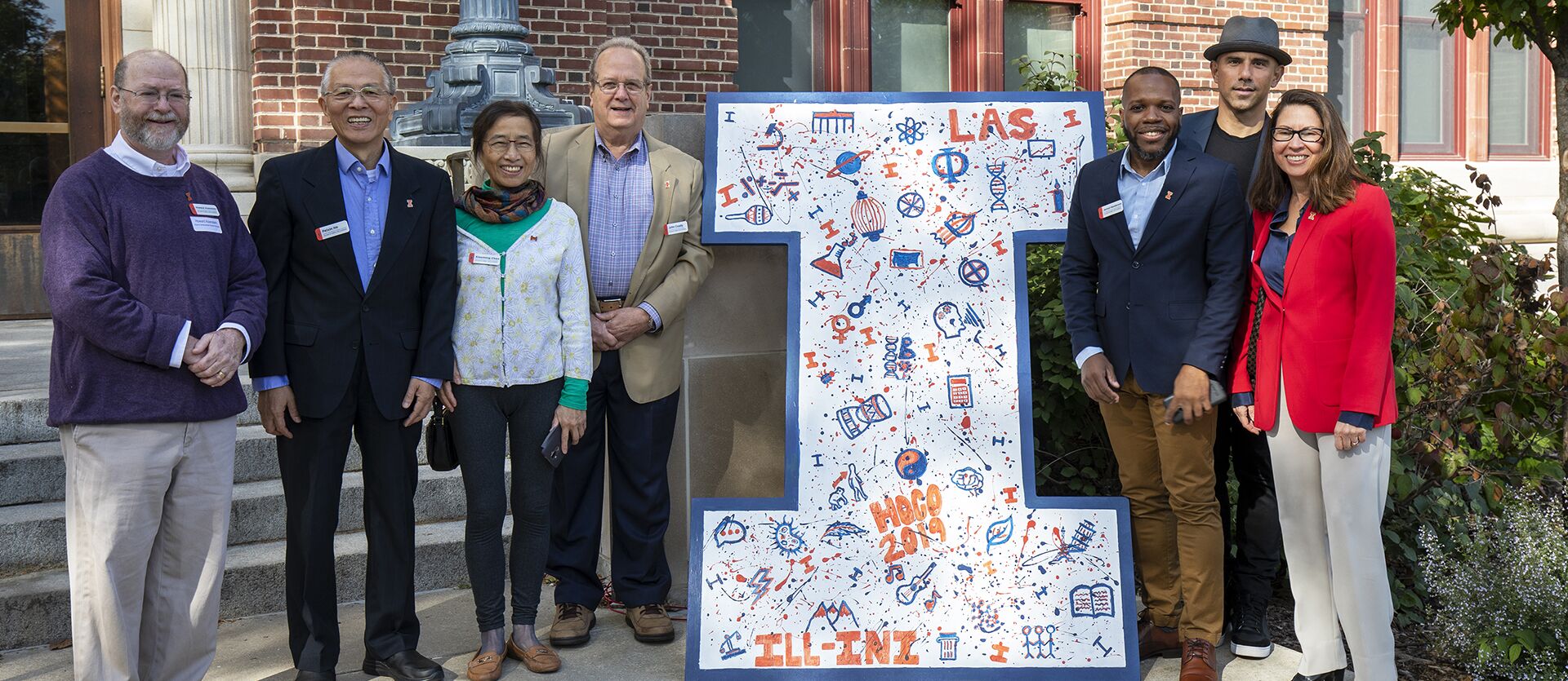 Alumni award winners pose near a white letter "I"