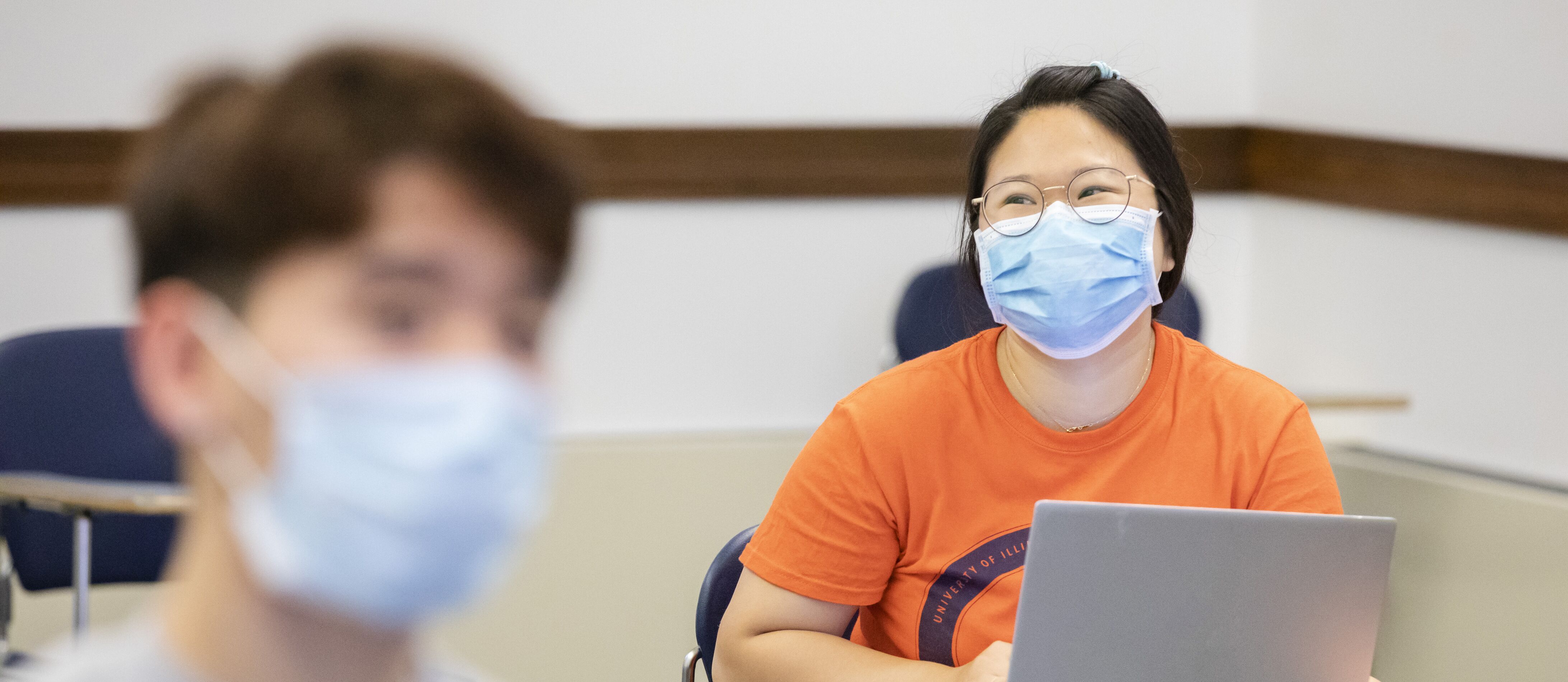 A student participates in a discussion in class while wearing a mask